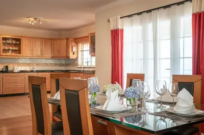 a dining room with a table with chairs and a kitchen at SUNNYSIDE VILLA in Calheta