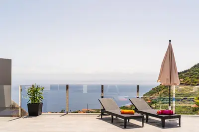 a patio with two chairs and a view of the ocean at SUNNYSIDE VILLA in Calheta