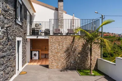 a house with a balcony with a palm tree at Casa Da Portada in Calheta