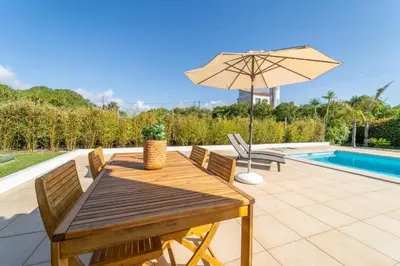 a wooden table with an umbrella next to a pool at Casa Onda - Fabulous Ocean View Villa in Aljezur