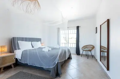 a bedroom with a bed and a chair in it at Casa Onda - Fabulous Ocean View Villa in Aljezur