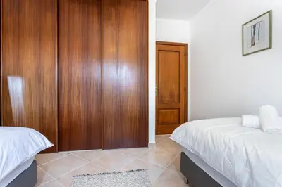a bedroom with two beds and a wooden closet at Casa Onda - Fabulous Ocean View Villa in Aljezur