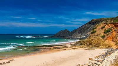 a beach next to the ocean with a cliff at Casa Onda - Fabulous Ocean View Villa in Aljezur