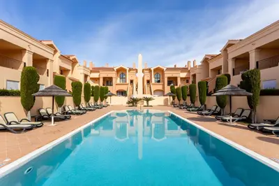 a pool in the courtyard of a hotel with chairs and umbrellas at Sun and Sea - Baia da Luz Apartment in Luz
