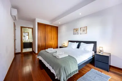 a bedroom with a large bed and a wooden floor at Sun and Sea - Baia da Luz Apartment in Luz