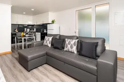 a living room with a black couch and a kitchen at Casa Terra-Boa in Arco da Calheta
