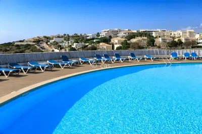 a swimming pool with blue chairs and avisorvisor at Beachfront Apartments Porto de Mós Beach - Lagos in Lagos