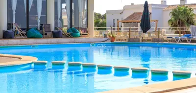 a large blue swimming pool with chairs and an umbrella at Beachfront Apartments Porto de Mós Beach - Lagos in Lagos