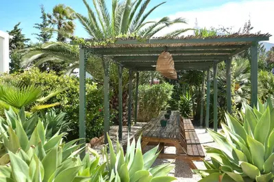 a wooden pergola with a bench in a garden at AltaVista Lodge in Luz