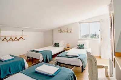 a room with three beds with green and white sheets at AltaVista Lodge in Luz
