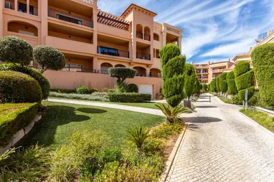 a garden in front of a building with trees and bushes at Rock and Sea - Baia da Luz in Luz