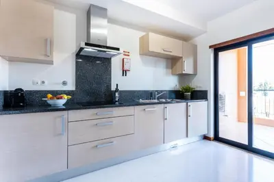 a kitchen with white cabinets and black counter tops at Rock and Sea - Baia da Luz in Luz