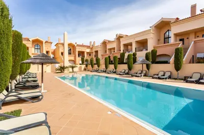 a resort pool with lounge chairs and umbrellas at Rock and Sea - Baia da Luz in Luz