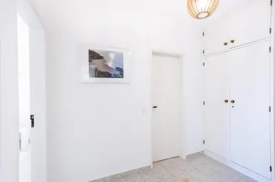 a room with white walls and a chandelier at Paraíso dos Pássaros in Budens