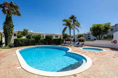 a swimming pool in a resort with palm trees at Paraíso dos Pássaros in Budens