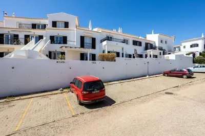 a red car parked in a parking lot in front of a building at Paraíso dos Pássaros in Budens