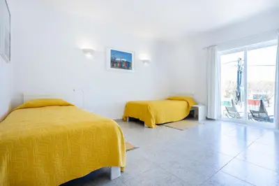 two beds in a white room with yellow sheets at Paraíso dos Pássaros in Budens