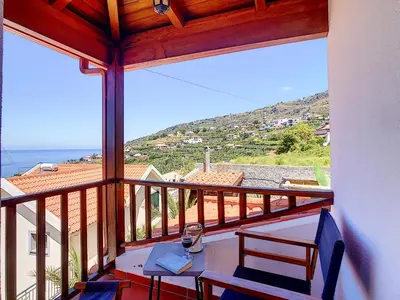 a balcony with a table and chairs and the ocean at Pôr do Sol by LovelyStay in Calheta