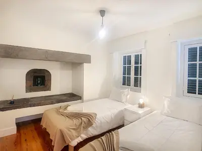 two beds in a white room with a fireplace at Casa Conceição by LovelyStay in Funchal