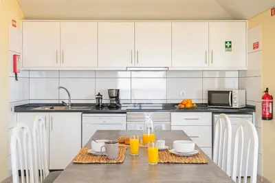 a kitchen with white cabinets and a table with orange juice at OurMadeira - SeaView Apartment in Calheta