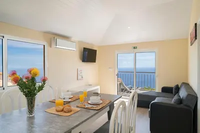 a living room with a table with a vase of flowers at OurMadeira - SeaView Apartment in Calheta