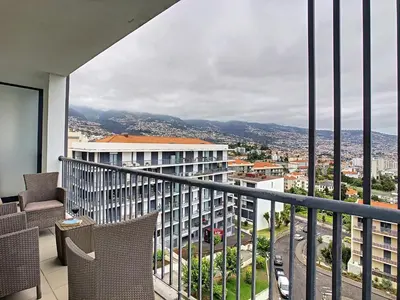 a balcony with chairs and a view of a city at Gemini Apartment by LovelyStay in Funchal