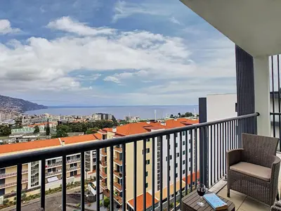 a balcony with a chair and a view of a city at Gemini Apartment by LovelyStay in Funchal