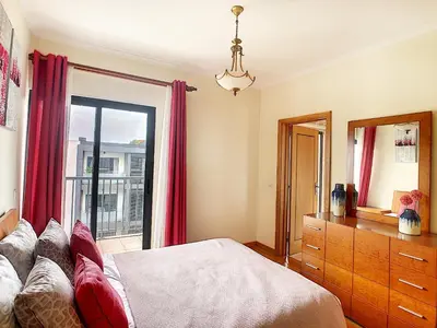 a bedroom with a bed and a window with red curtains at Gemini Apartment by LovelyStay in Funchal