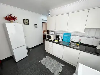 a kitchen with white cabinets and a white refrigerator at Comfortable 2-Bedroom Apartment for Relaxing Stays in Funchal