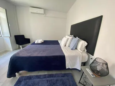 a bedroom with a bed with a blue blanket and pillows at Zoe House in Paul do Mar