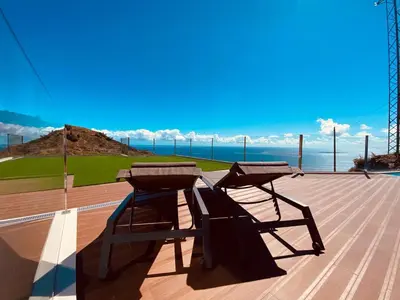 a picnic table and bench on a deck with the ocean at Villas Calhau da Lapa 51 in Campanário