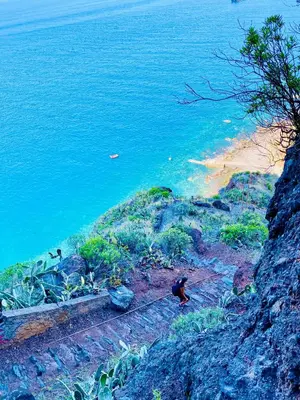 a person walking down a hill next to the water at Villas Calhau da Lapa 51 in Campanário