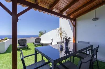a patio with a table and chairs and the ocean at Flowers island house 3 in Caniço