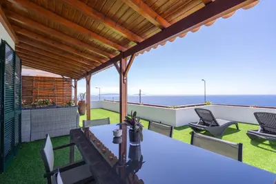 a patio with a table and chairs and the ocean at Flowers island house 3 in Caniço