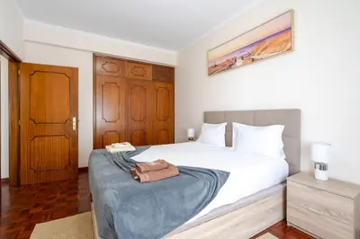 a bedroom with a white bed with a blue blanket on it at Flowers island house 3 in Caniço