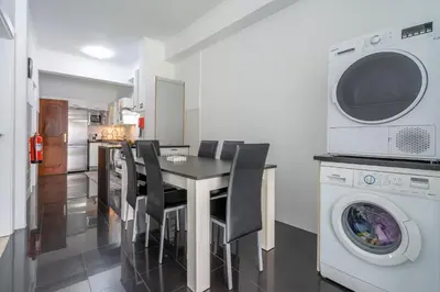 a kitchen with a table and chairs and a washing machine at Flowers island house 3 in Caniço