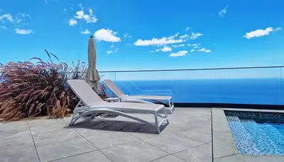two chairs and an umbrella next to a swimming pool at Villa Estrelícia by LovelyStay in Ribeira Brava