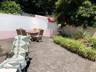 a patio with a table and chairs in a garden at Quintinha de Palmyra in Camacha