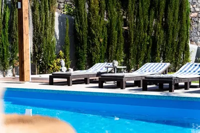 three lounge chairs and a swimming pool with trees at GALVÃO HOUSE EXPERIENCE in Ribeira Brava