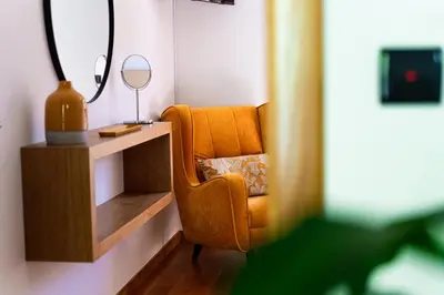 a living room with a chair and a mirror at GALVÃO HOUSE EXPERIENCE in Ribeira Brava