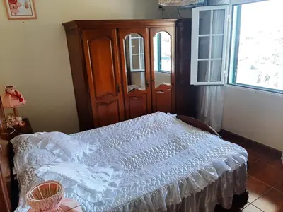 a bedroom with a bed with a wooden cabinet and a window at Casa do Terço in Câmara de Lobos