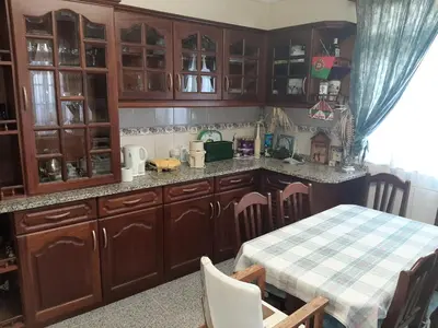 a kitchen with wooden cabinets and a table at Casa do Terço in Câmara de Lobos