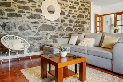 a living room with a couch and a stone wall at Sea View Villa by Homie in Santa Cruz