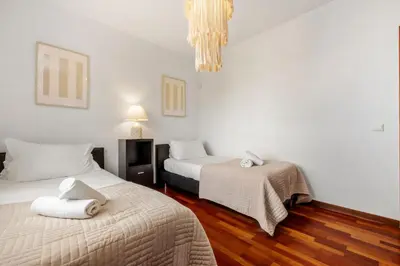 two beds in a room with white walls and wood floors at Sea View Villa by Homie in Santa Cruz
