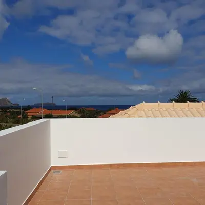 a white wall with a tile floor next to a building at Casa Azul in Porto Santo