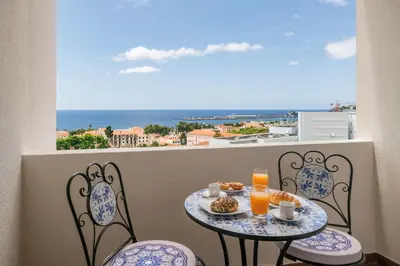 a table and chairs on a balcony with a view of the ocean at Alegria III by An Island Apart in Funchal