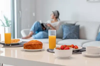 a woman laying on a couch with a table with food and orange juice at Alameda Formosa I by An Island Apart in Funchal