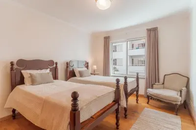 a bedroom with two beds and a chair and a window at Residência Costa do Sol in Funchal