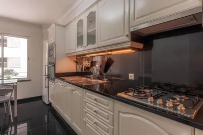 a kitchen with white cabinets and a sink and a stove at Residência Costa do Sol in Funchal