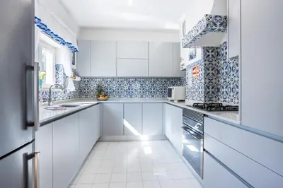 a kitchen with white cabinets and blue and white tiles at Sea Blue Apartment - Luz Ocean Club in Luz